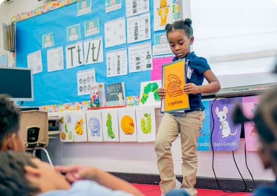 An elementary student practices communication skills by leading the class