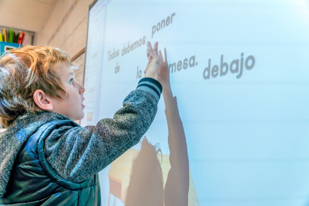 A Spanish DL student at participating in a lesson at a SmartBoard