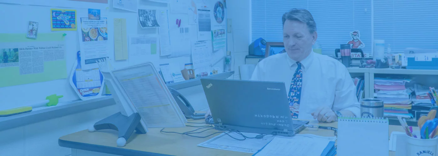 An administrator from a Participate Learning Network school sitting at a desk on a laptop
