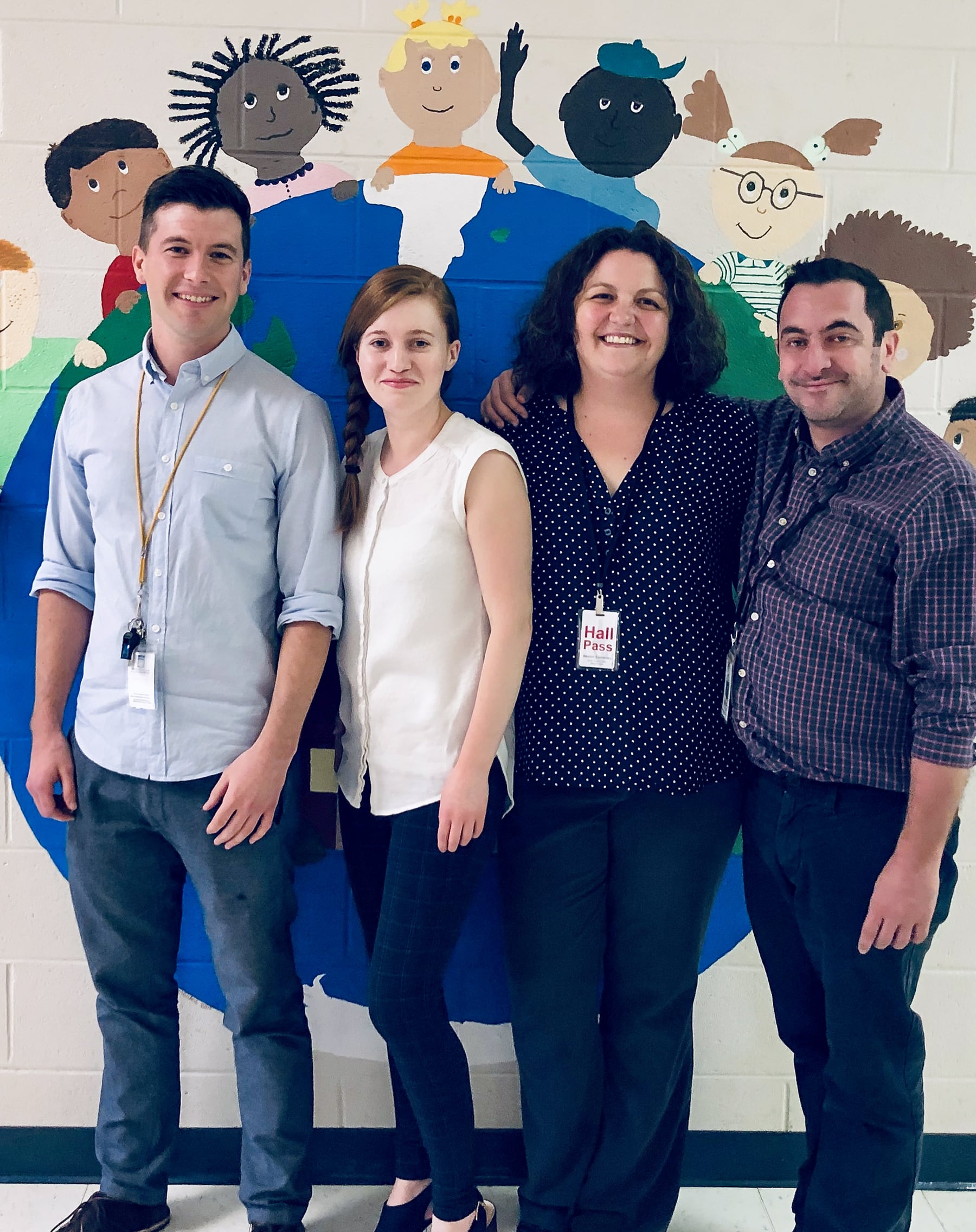 Baucom Elementary’s international teachers smile in front of a colorful wall mural