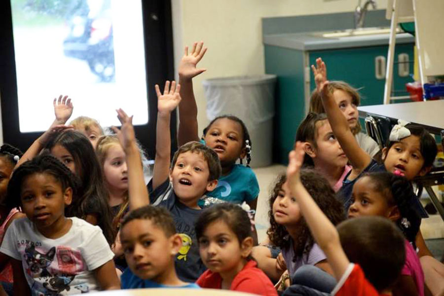 Dual language students raising their hands to answer questions, engaging in deeper learning