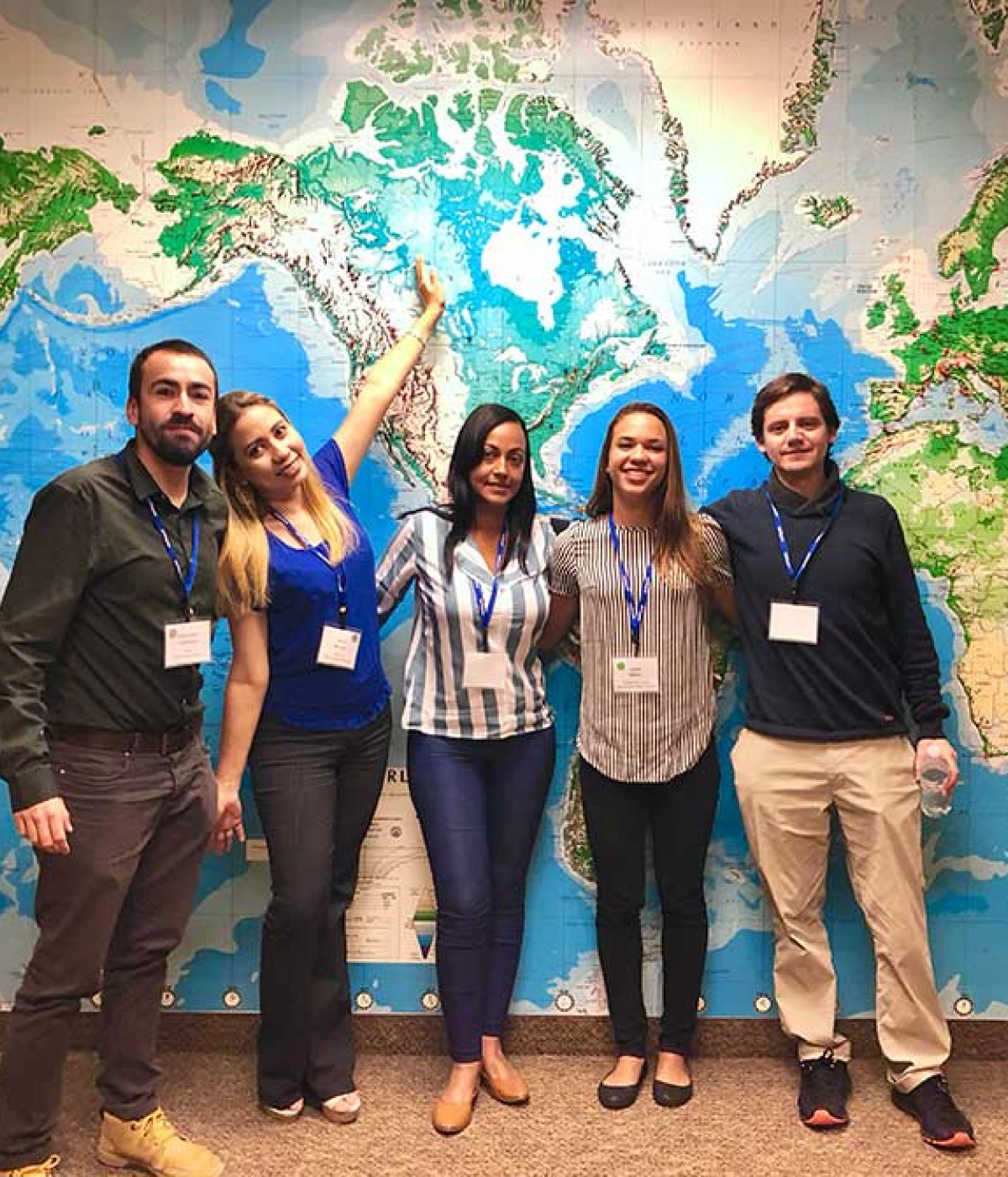 Ambassador Teachers in the Participate Learning program smile in front of a world map