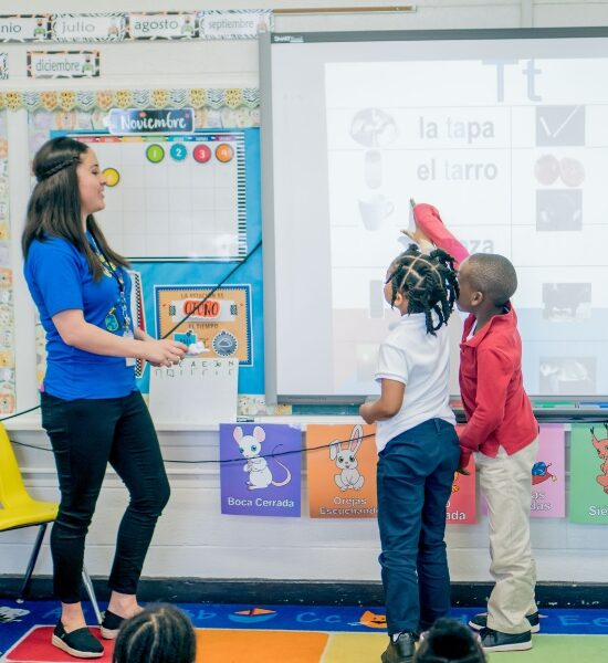 A Spanish dual language program classroom with a teacher and two students at a Smart Board
