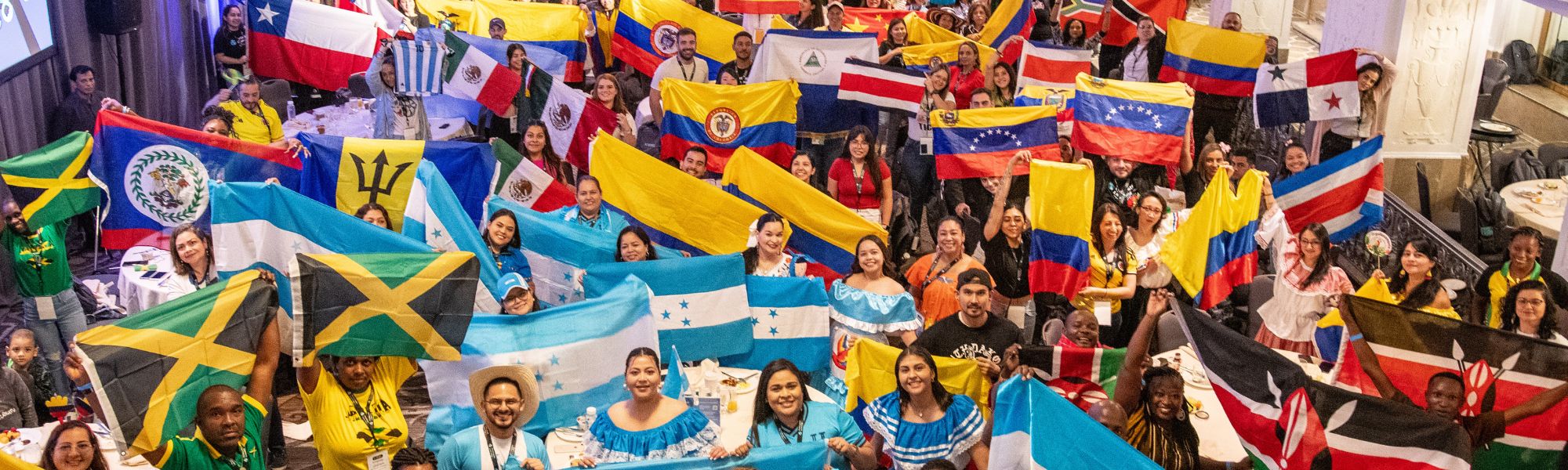 Large group of exchange teachers smiling and posed with flags from countries like Chile, Argentina, Honduras, Colombia, and Ecuador.