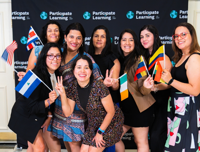 International teachers posing with flags at Participate Learning's BridgeUSA J-1 visa cultural exchange teaching program orientation