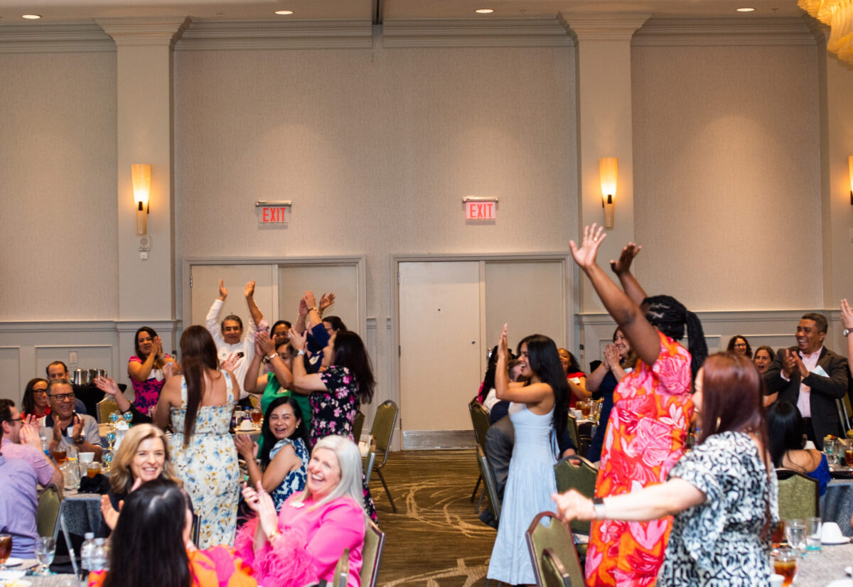 People standing up and cheering at Ambassador Teacher Graduation