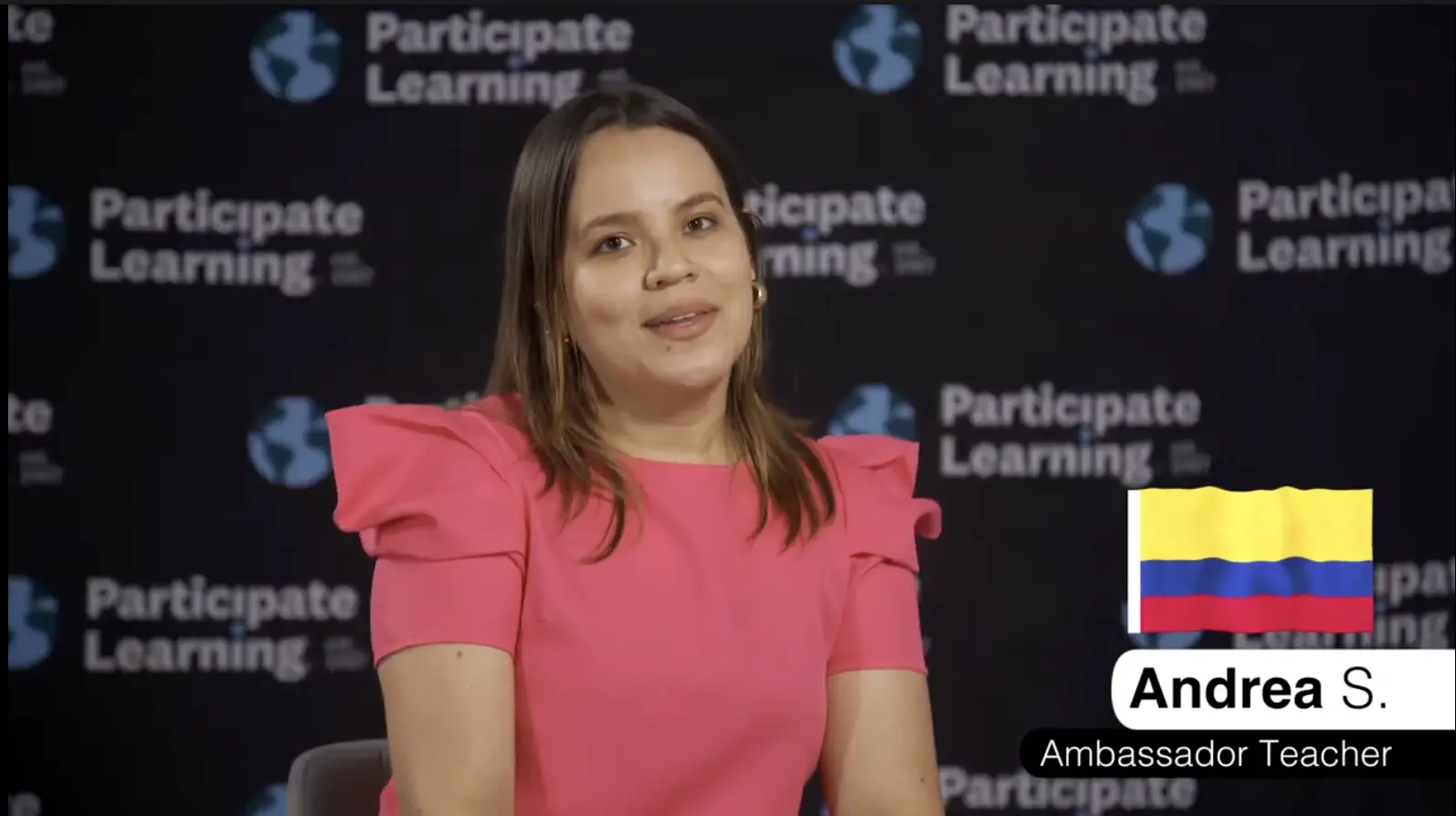 An Ambassador Teacher from Colombia named Andrea S. participates in a cultural exchange program, sharing her experience teaching in the United States. She is wearing a bright pink blouse and smiling while seated in front of a "Participate Learning" branded backdrop. The image emphasizes opportunities for teaching abroad, professional growth, and cultural exchange through programs that support educators who want to teach in the U.S.