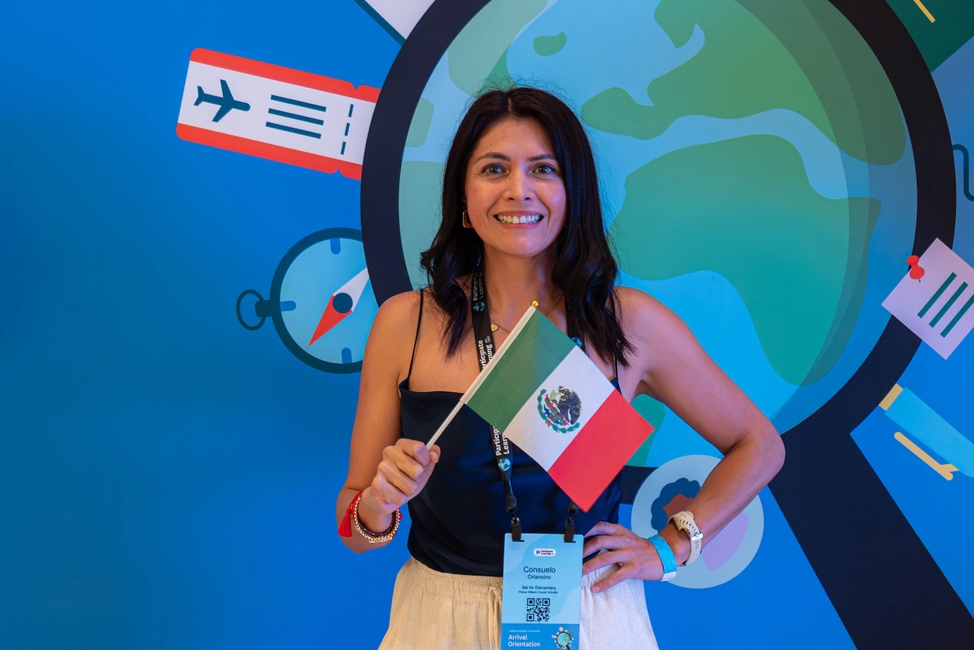 Educator from Mexico smiles while holding the national flag at Participate Learning orientation, ready to begin her cultural exchange teaching experience in the U.S.