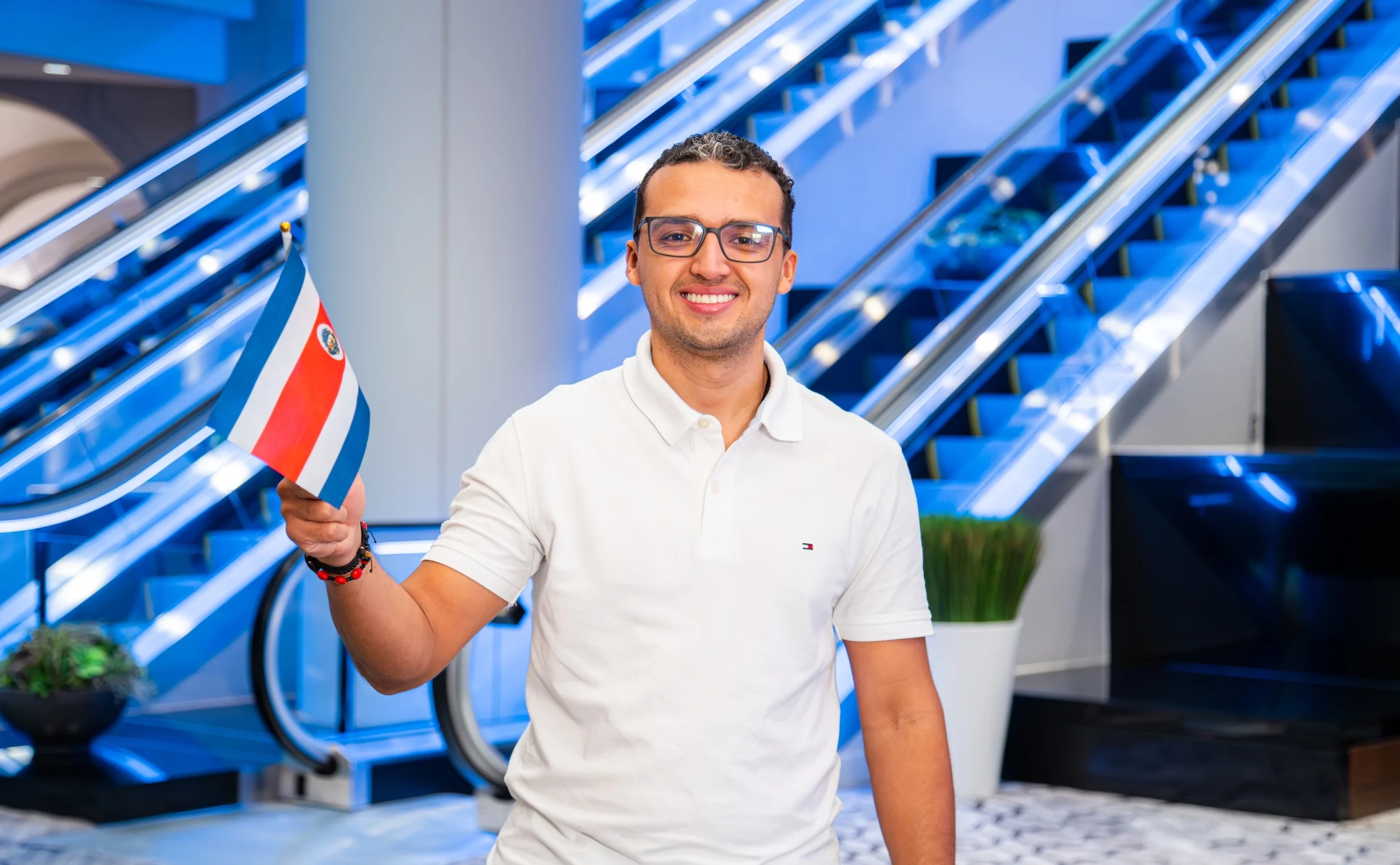 Educator from Costa Rica smiles while waving the national flag at Participate Learning orientation, ready to begin teaching in U.S. classrooms through the exchange program.