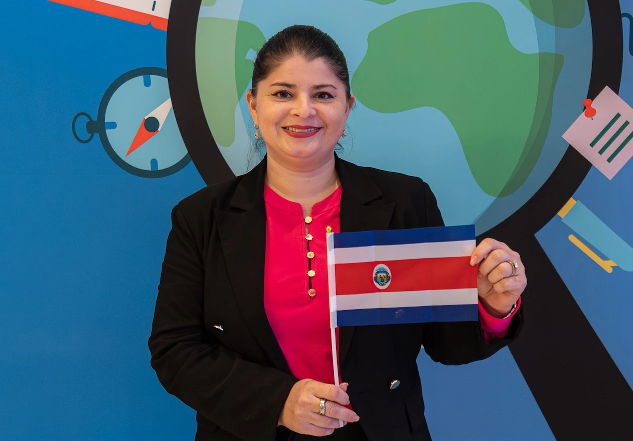 Teacher from Costa Rica holds her national flag during Participate Learning orientation, proudly representing her country as part of the cultural exchange program.