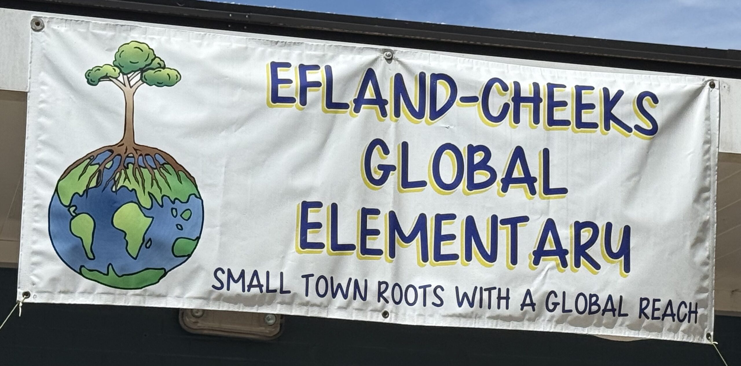 School banner reading “Efland-Cheeks Global Elementary, Small town roots with a global reach” with a globe and tree graphic.
