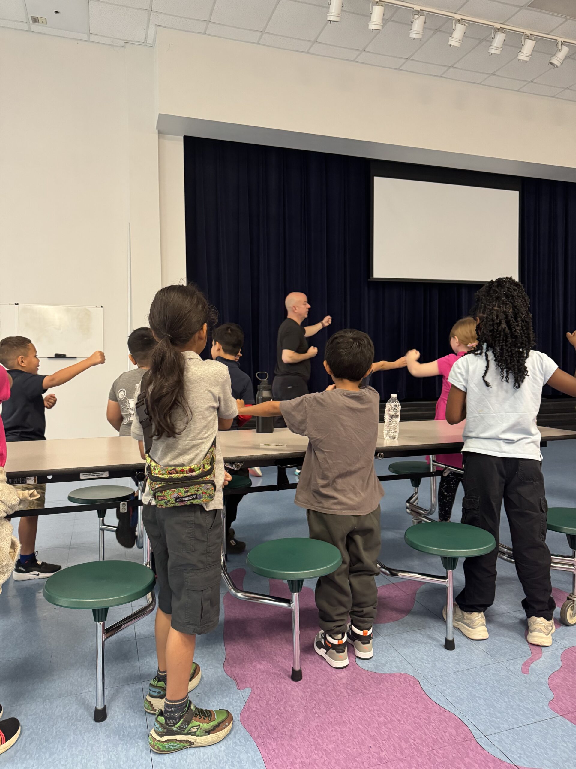 Elementary students practicing martial arts movements with an instructor during a school enrichment activity supporting career exploration and global competencies through active learning.