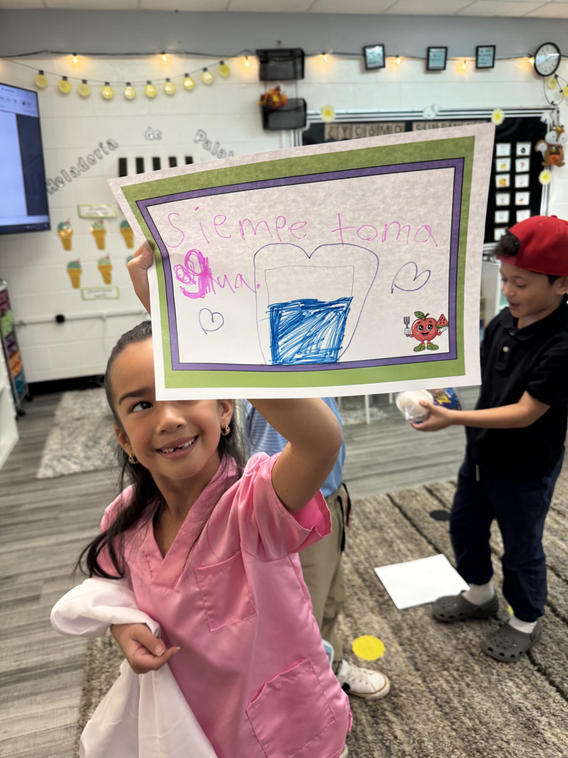A student holds up a healthy habits poster she made that says "Siempre toma agua," or "Always drink water"