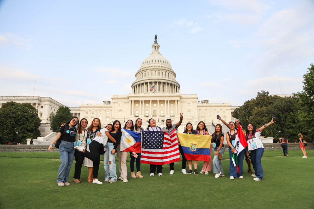 A group of Participate Learning Ambassador Teachers holds national flags while posing in front of the U.S. Capitol in Washington, D.C.