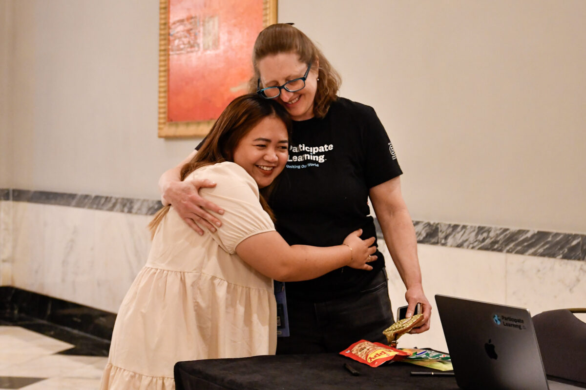 An international teacher hugs a Participate Learning staff member. 